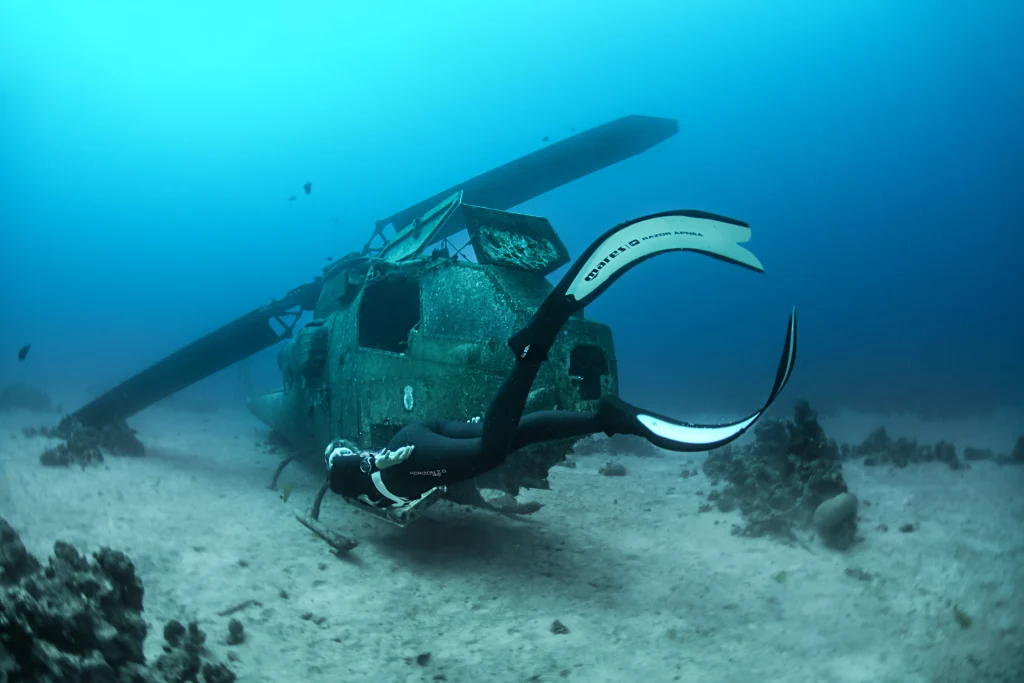 épave d'hélicoptère sur fond marin avec plongeur devant